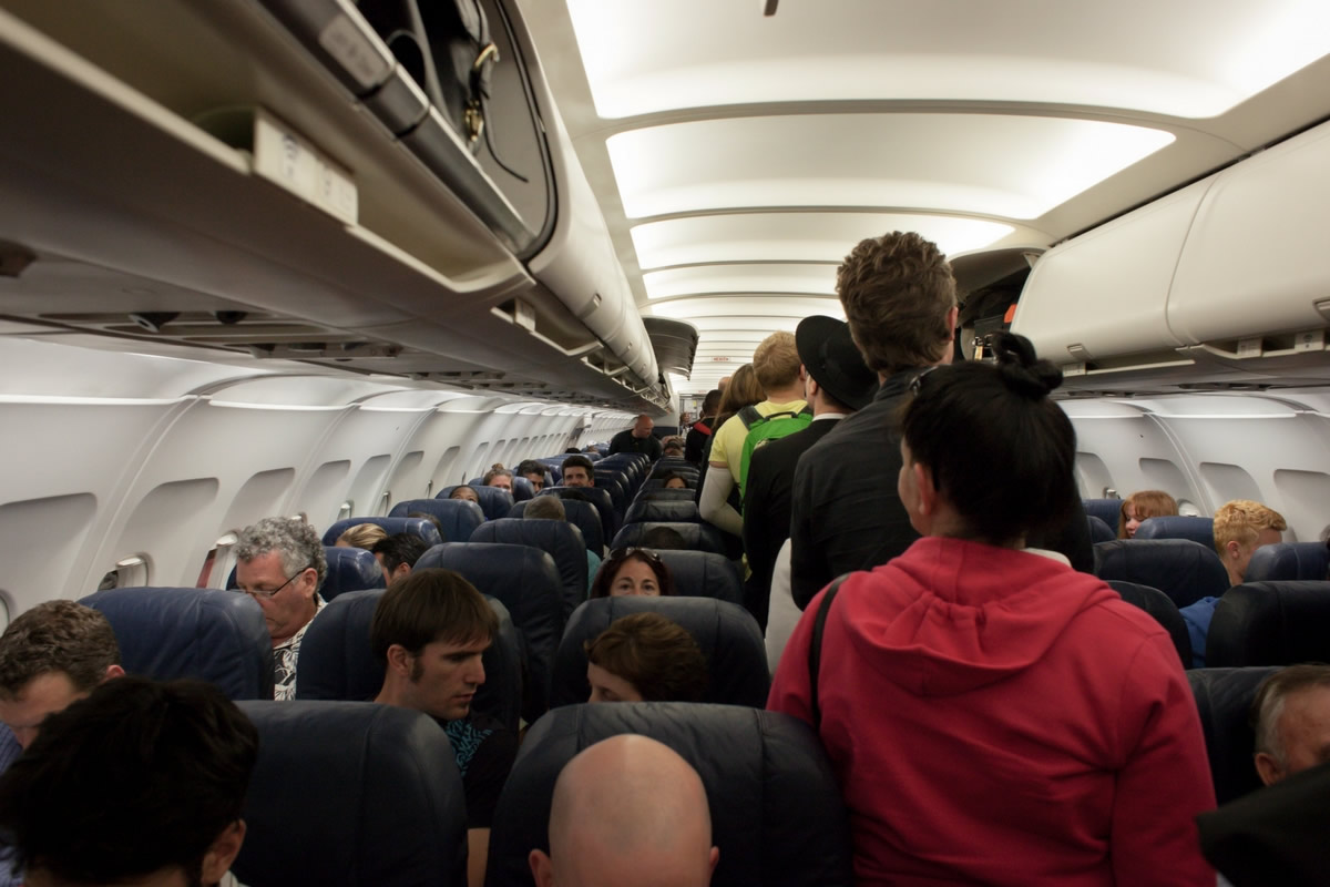 pessoas dentro da aeronave procurando seus assentos