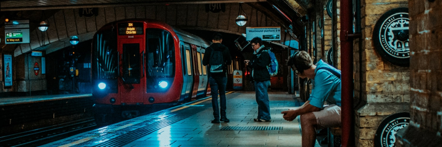 homem sentado na estação vendo trem chegar