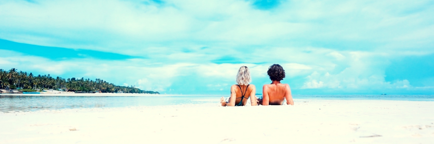 casal sentado na areia na beira mar